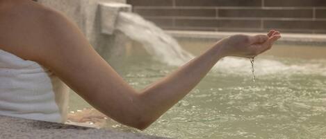 Una persona en una bañera con agua fluyendo de su mano.
