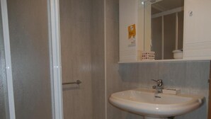 A bathroom with a shower, a sink, and a mirror. - Hostal El Volante (Estella)