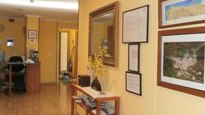 A room with a wooden desk, a vase with flowers, framed pictures on the wall, and a mirror. - Hostal El Volante (Estella)