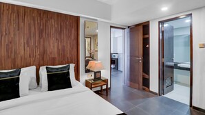Ein Hotelzimmer mit einem großen Bett, einem Nachttisch mit Lampe, einem Spiegel und einer Tür zu einem Badezimmer.
