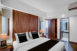 A hotel room with a large bed, a wooden headboard, a bedside table with a lamp, and a bathroom visible through an open door. - Palette Hotel Seminyak  (Seminyak)