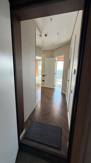 Ein Flur mit Holzboden, Fußmatte und Tür zu einem Zimmer mit Fenster.