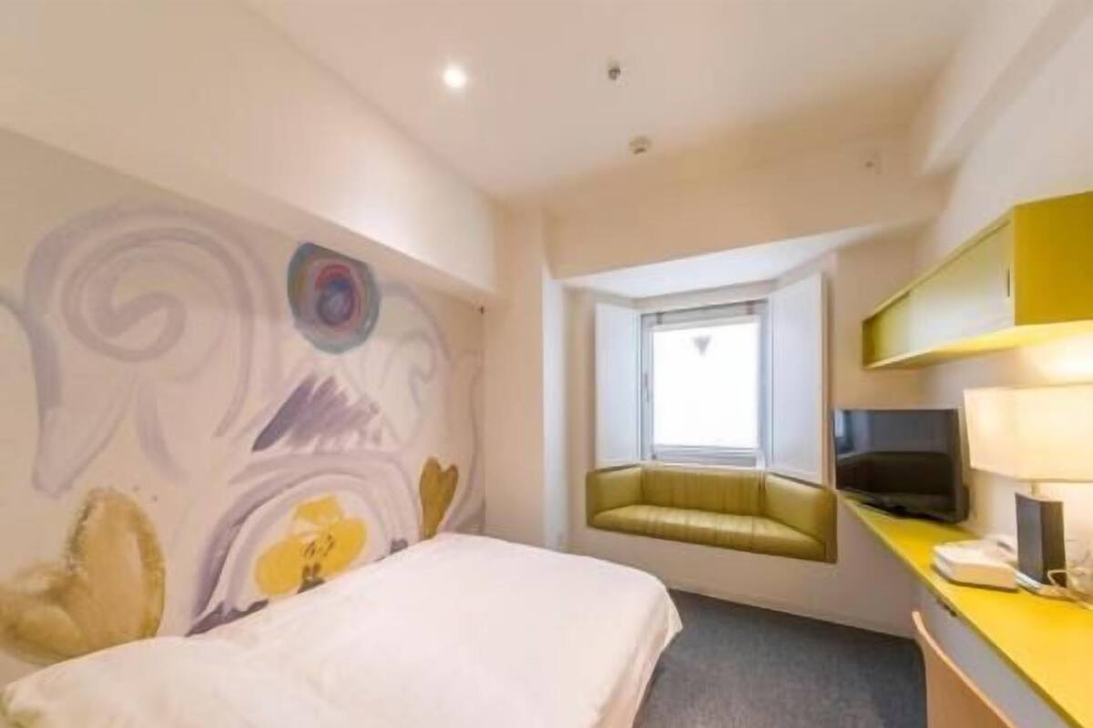 Ein Hotelzimmer mit einem Bett, einem Schreibtisch mit Lampe, einem Fernseher und einem Fenster mit Blick.