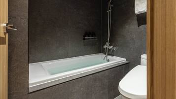 A modern bathroom with a built-in bathtub, a toilet, and a shower.