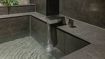 A modern water feature with a cascading design, set in a dark-toned stone structure.