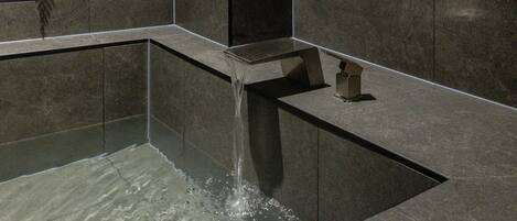 A modern water feature with a cascading design, set in a dark-toned stone structure.