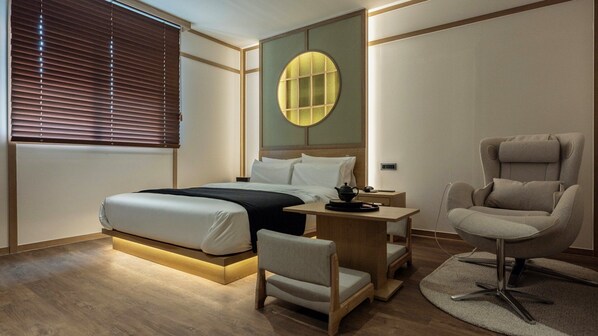 Un dormitorio moderno con cama, mesita de noche, silla y un llamativo elemento circular en la pared.
