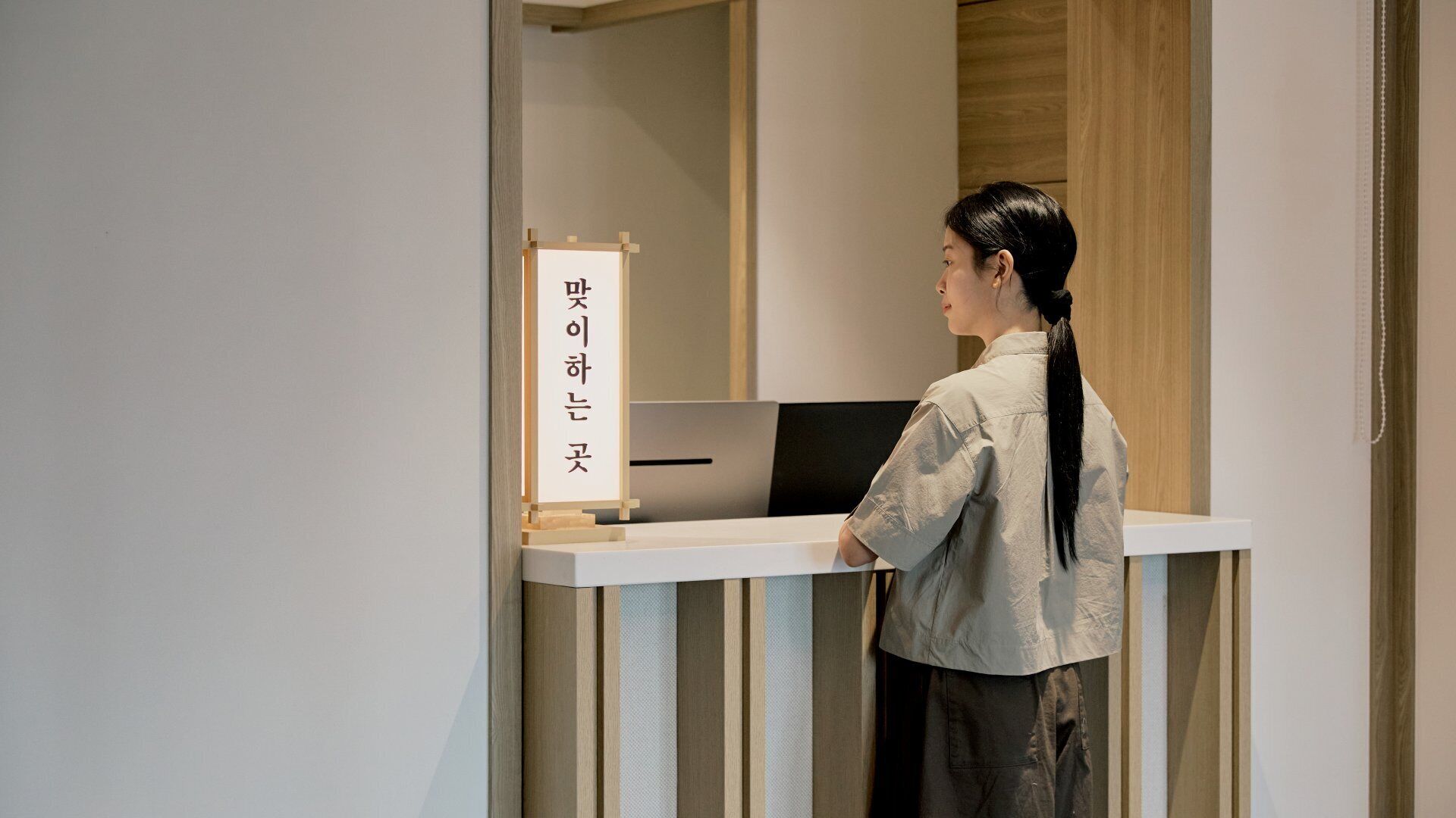 A person standing at a reception desk with a sign that has text on it.