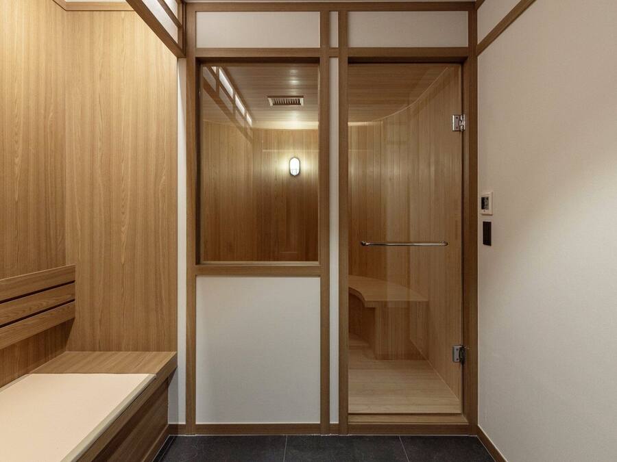 A wooden interior with a bench, a sliding door, and a light fixture.
