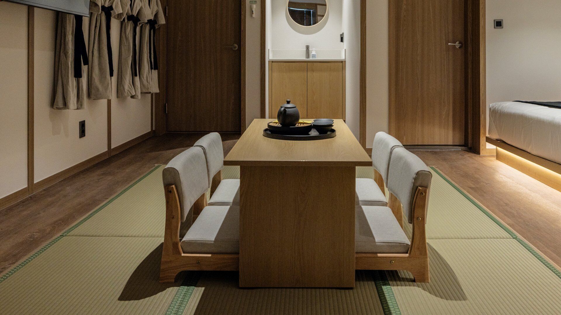 A traditional Japanese-style room with tatami flooring, a low wooden table, and a futon bed.