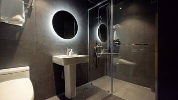 A modern bathroom with a glass shower enclosure, a pedestal sink, and a toilet.