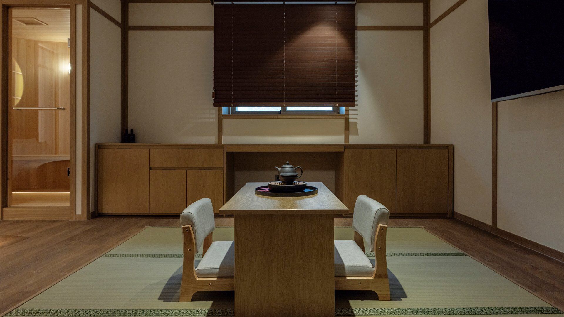 Una habitación de estilo japonés tradicional con suelo de tatami, una mesa baja con un juego de té y puertas correderas shoji.