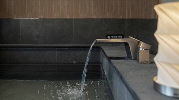 A modern bathroom with a black countertop, a faucet, and a visible water stream.