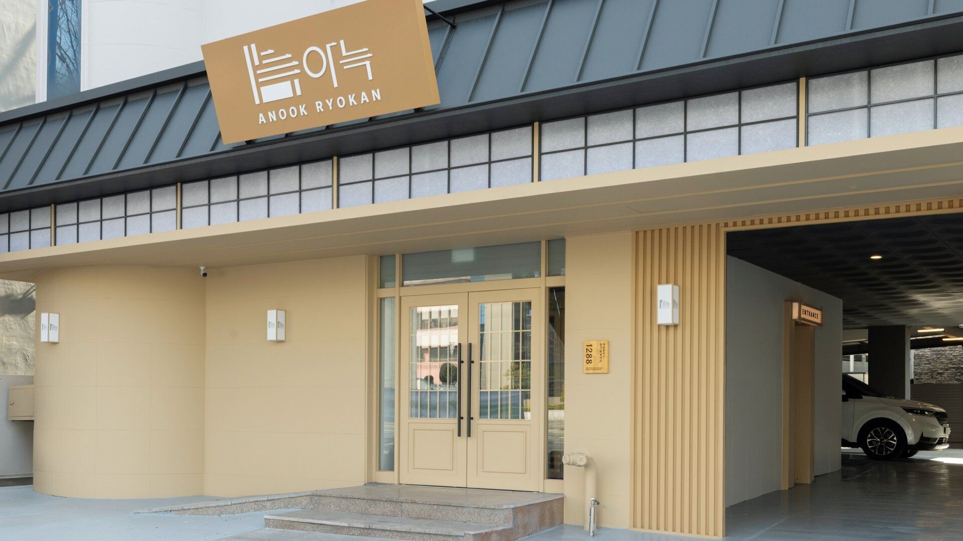 A building with a sign reading 'ANOOK RYOKAN' and a car parked inside.