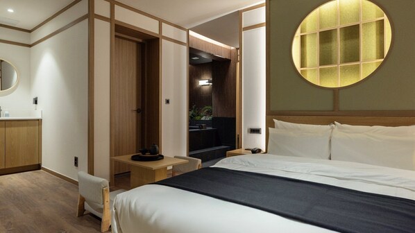 A hotel room with a bed, bedside table, mirror, and a view of a bathroom. - Anook Ryokan Hotel Daejeon Yongjeon (Daejeon)