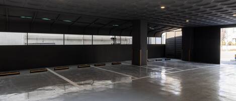 Un parking souterrain vide, avec un sol mouillé, des piliers en béton et un plafond à motifs.