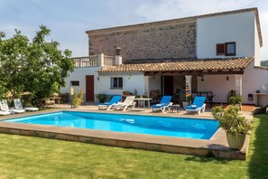 A two-story house with a swimming pool, outdoor seating, and a stone wall. - Villa 'Suari' with Mountain View, Private Pool and Wi-Fi (Illes Balears)