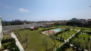 Un cortile con piscina, zona salotto coperta e prato verde.