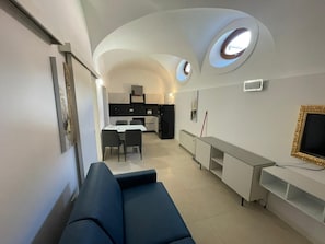 Un interno moderno con un divano, un tavolo da pranzo, angolo cottura e TV a incasso.