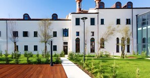 A modern building with a white facade, multiple windows, and a well-maintained lawn.