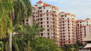 A multi-story residential building with balconies, surrounded by greenery and parked cars.