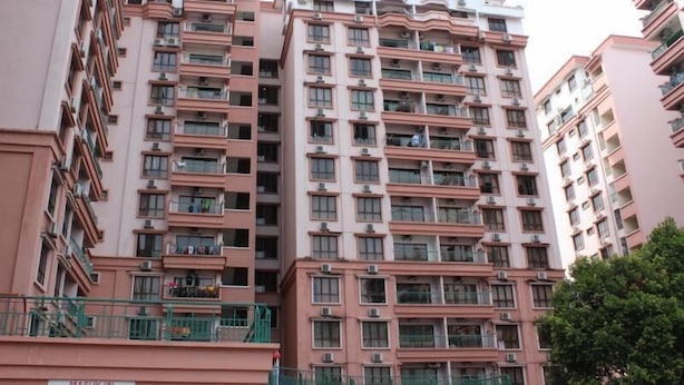 Edifício residencial com várias andares, varandas, aparelhos de ar condicionado e um aviso indicando estacionamento.