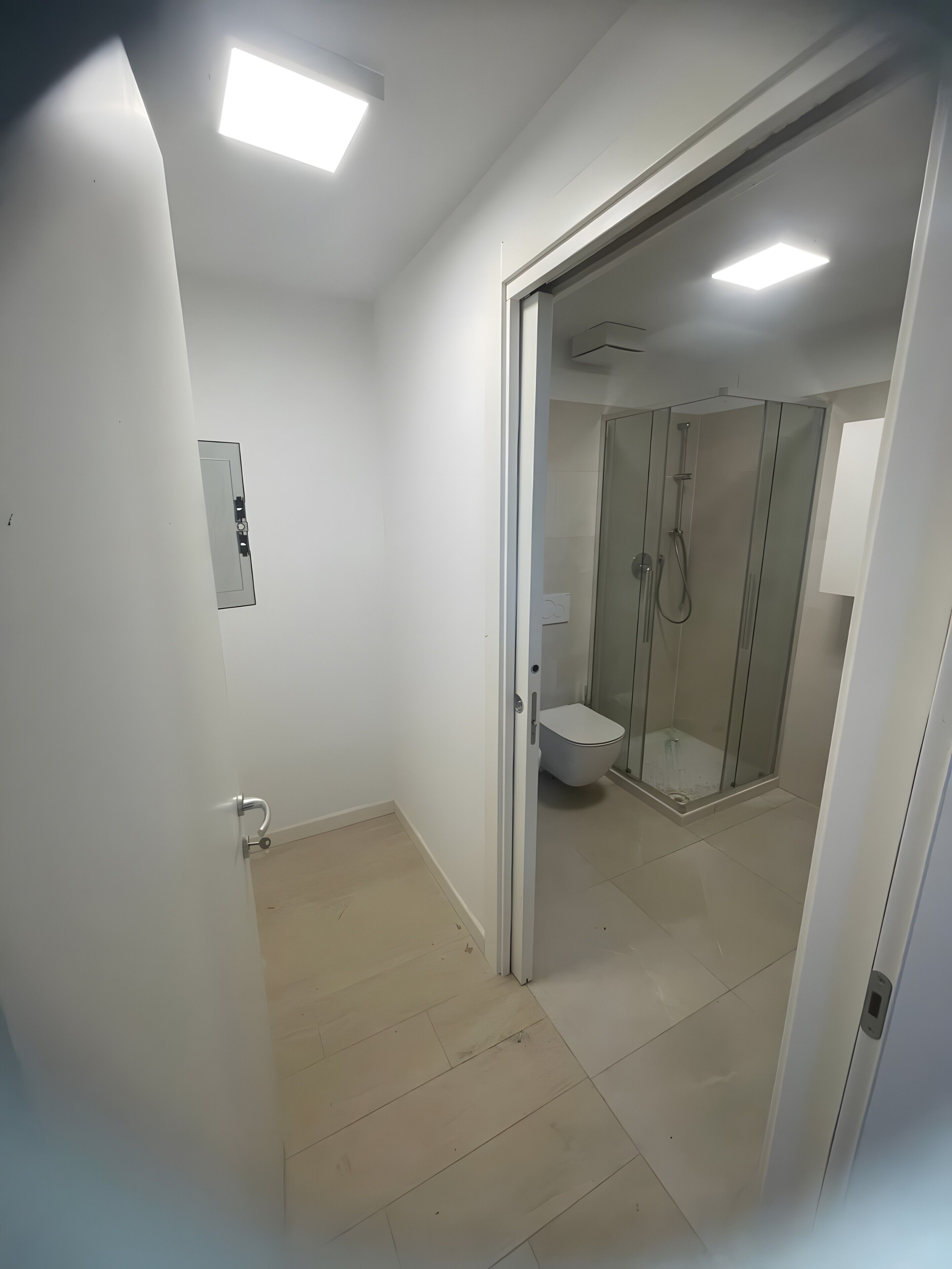Un baño moderno con inodoro, ducha y cabina de ducha con paredes de vidrio.