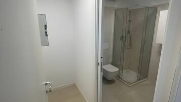 Un baño moderno con inodoro, ducha y cabina de ducha con paredes de vidrio.