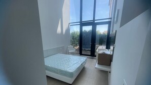 A modern bedroom with a large bed, a small seating area, and a view through a glass door. - Spacious Apartment for 6 Guests – Elevator Access near Venice (Venezia)