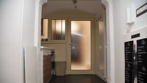 A hallway with a kitchen area, a door with frosted glass panels, and a wall-mounted phone.