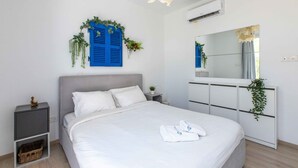 A bedroom with a bed, bedside tables, a dresser, a mirror, and wall-mounted plants. - Lemon Tree 1-BR Apt & Pool in Livadia (Larnaca)