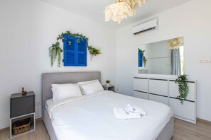 A bedroom with a bed, bedside tables, a dresser, a mirror, and wall-mounted plants. - Lemon Tree 1-BR Apt & Pool in Livadia (Larnaca)