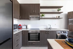 Une cuisine moderne avec des meubles de couleur bois foncé, une cuisinière en acier inoxydable, un four encastré, un lave-vaisselle et un four à micro-ondes.