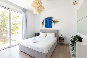 Un dormitorio moderno con una cama grande, una mesita de noche, un estante en la pared con plantas y una ventana con cortinas.