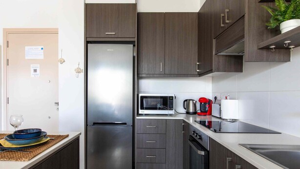 A modern kitchen with a stainless steel refrigerator, a microwave, a coffee maker, and a sink. - Lemon Tree 1-BR Apt & Pool in Livadia (Larnaca)