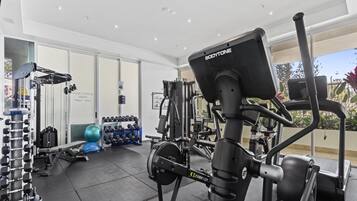 A gym with various exercise equipment, including a stationary bike, dumbbells, and weight machines.