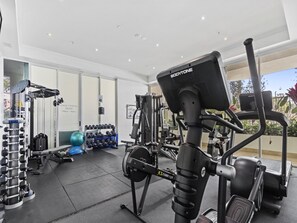 A gym with various exercise equipment, including a stationary bike, dumbbells, and weight machines. - Bright 2 Bed Apartment With Ocean Views (Gold Coast)