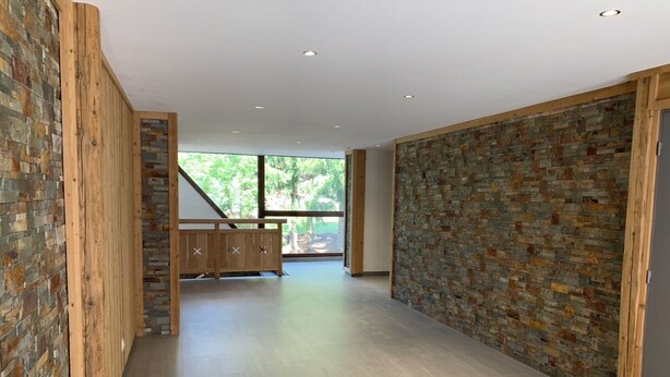 A modern interior with a wooden bench, stone walls, and a view of greenery. - Les 2 alpes, at the foot of the slopes - apartments (Les Deux Alpes)