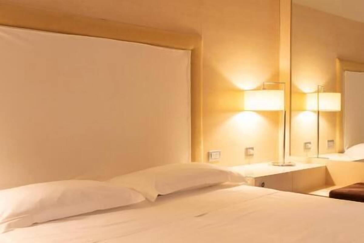 Una habitación de hotel con una cama grande, una mesita de noche y un espejo.
