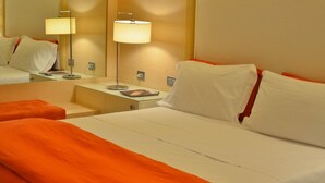 Una habitación de hotel con cama, mesita de noche, lámpara y espejo.