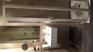 Una habitación con cama, mesita de noche, espejo y ventana.