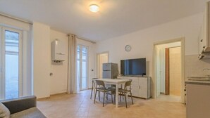 Un appartamento moderno con zona pranzo, TV e angolo cottura.