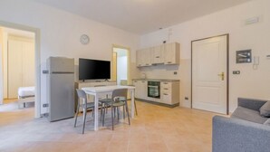 Un ambiente compatto con angolo ristoro, angolo cottura e televisione.