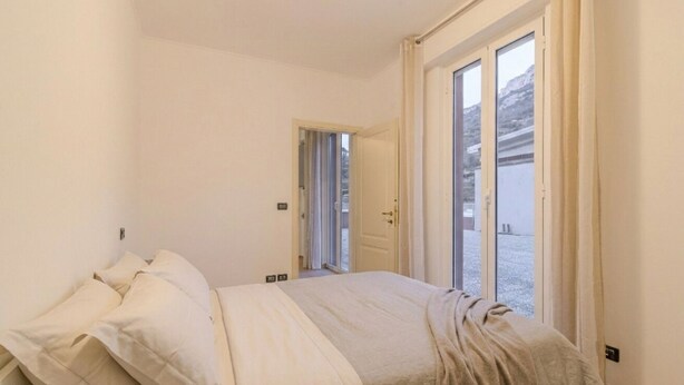 Una camera da letto con un letto, una porta che dà su un balcone e vista su un paesaggio montuoso.