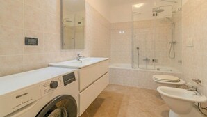 Un baño moderno con lavadora, bañera, inodoro y bidé.