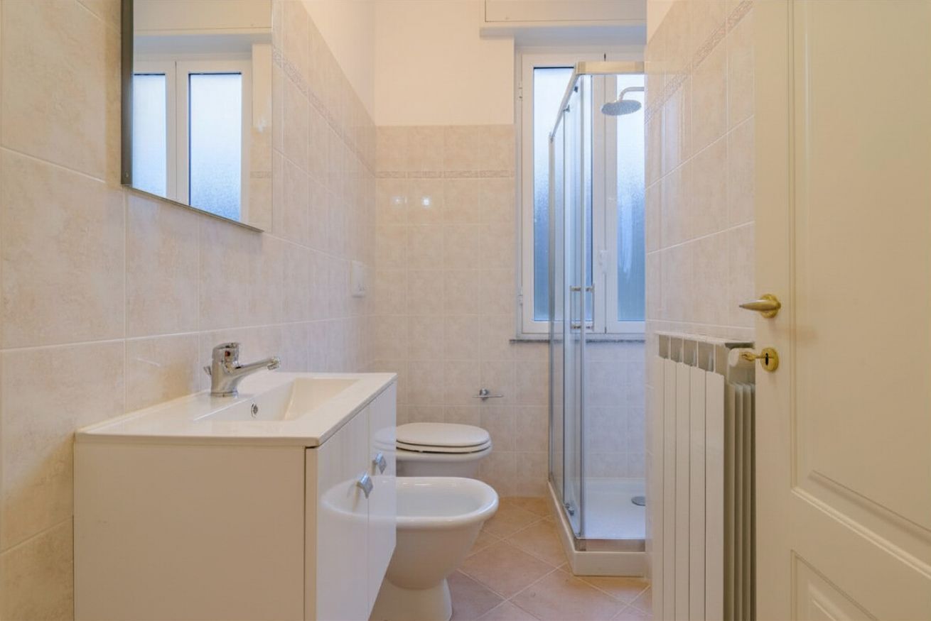 Et badeværelse med vask, toilet og bruser.