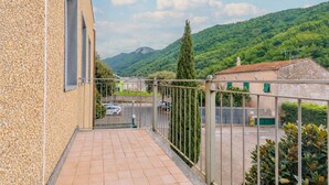 A balcony with a view of a road, a mountain, and a building with a tiled roof. - Piergi Bike Home 3 Finale Ligure (Finale Ligure)