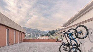 A rooftop terrace with a bicycle leaning against the wall, a view of a bridge, and a hilly landscape in the background. - Piergi Bike Home 3 Finale Ligure (Finale Ligure)