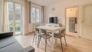 A modern kitchen with a dining table and chairs, a flat-screen TV, and a refrigerator. - Piergi Bike Home 3 Finale Ligure (Finale Ligure)