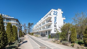Un hôtel moderne à plusieurs étages, doté de balcons, avec un ciel dégagé et une rue pavée.